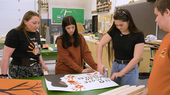 Four youth make a sign for Red Dress Day
